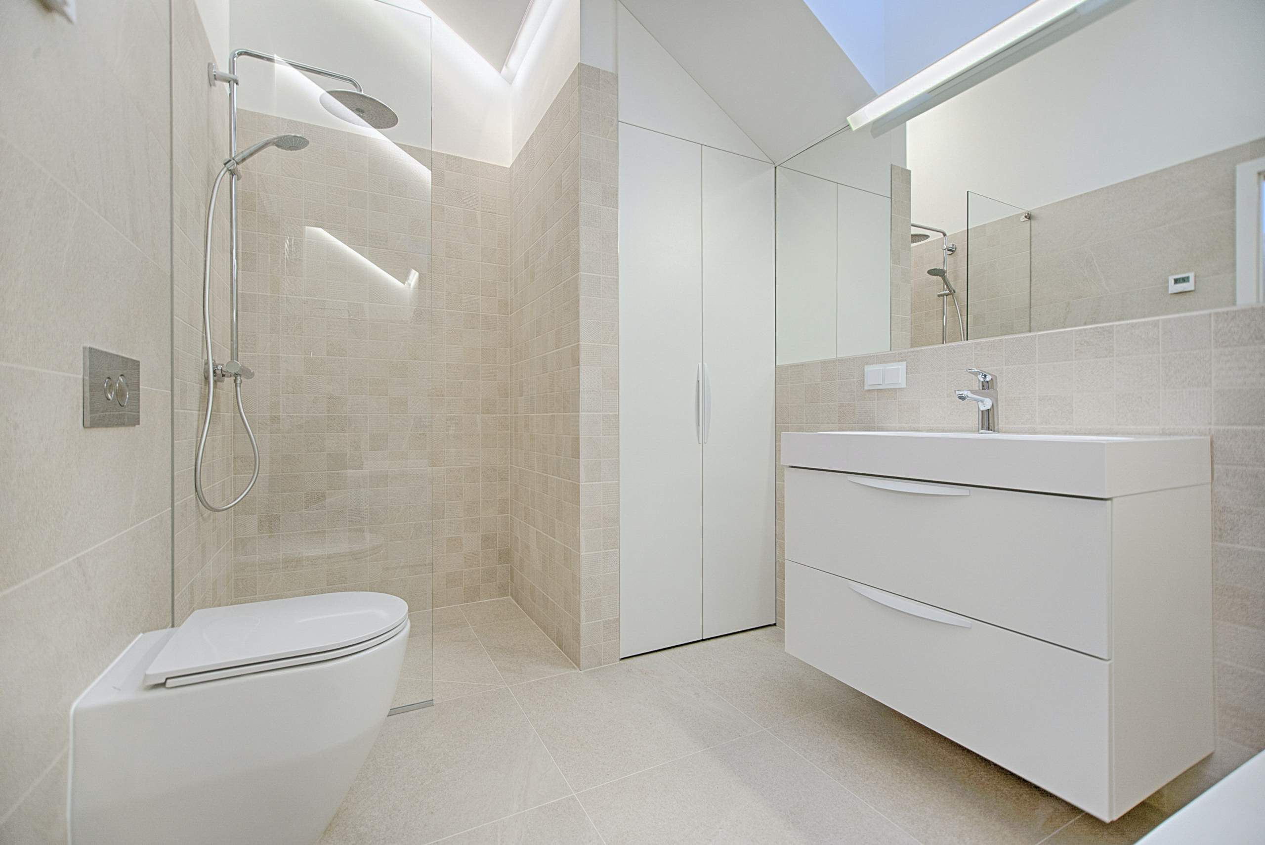 Das Bild zeigt ein Badezimmer, welches kurz zuvor gereinigt wurde. Es ist weiß und modern eingerichtet.